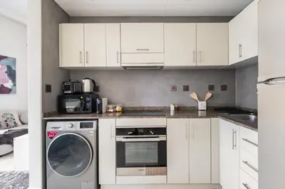 a kitchen with white cabinets and a dishwasher at Iolanda Home in Dubai
