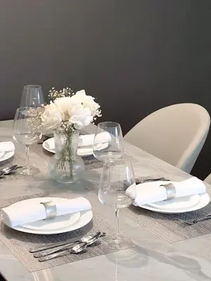 a table with white plates and wine glasses and flowers at GMA Amwaj 2BR Sea View High Floor in Dubai