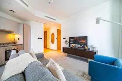 a living room with a blue couch and a tv at SettlerHomes - 2BR Downtown Haven, Ideal For Family Comfort in Dubai