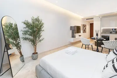 a bedroom with a white bed and a kitchen at Trendy Studio! Walk to Burj Khalifasleeps 3! in Dubai