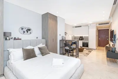 a bedroom with a large white bed and a kitchen at Designer Glam Studio Steps from Burj Khalifa in Dubai