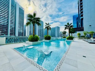 a swimming pool on a building with palm trees and buildings at Chic Studio with Burj Views at Sterling by Omniyat in Dubai