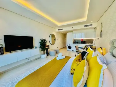 a living room with a large television and yellow pillows at Chic Studio with Burj Views at Sterling by Omniyat in Dubai