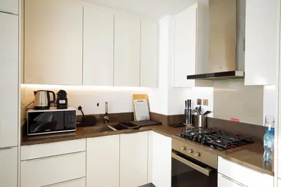 a white kitchen with white cabinets and a microwave at BRAND NEW LUXURY 1 BR Apartment at Marina Gate 2 full Marina view in Dubai
