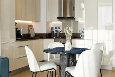 a kitchen with a table and white chairs at BRAND NEW LUXURY 1 BR Apartment at Marina Gate 2 full Marina view in Dubai