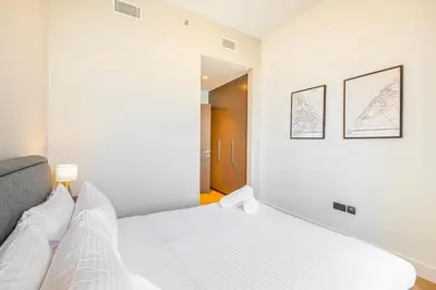 a bedroom with a white bed with two pictures on the wall at Daniels 3BR Urban Retreat with Downtown Views in Dubai