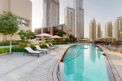 a swimming pool with chairs and umbrellas in a city at WhiteSage - Opera Grand Elegance 3BR with Burj Khalifa Views in Dubai