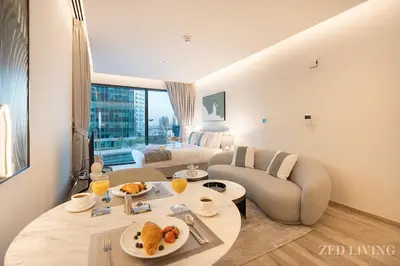 a living room with a couch and a table with food on it at Ahad Residences - City Retreat Apartments - Zed Living in Dubai