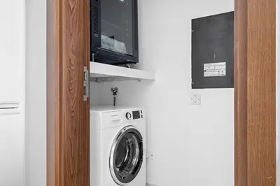 a washer and dryer with a tv on a wall at Luxury 1BR - Leisure Facilities Access - Sea View in Dubai