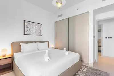 a bedroom with a white bed and a glass door at Luxurious Living in the heart of Emaar Beachfront in Dubai
