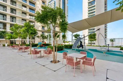 a patio with tables and chairs and a playground at Luxurious Living in the heart of Emaar Beachfront in Dubai