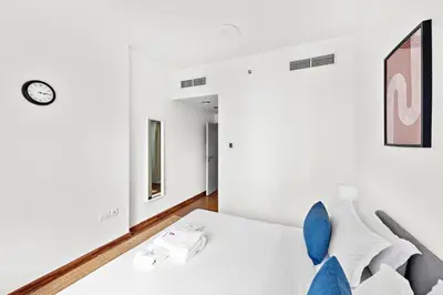 a bedroom with a white bed with blue pillows at StoneTree - Furnished 1BR in JLT with Lake View in Dubai