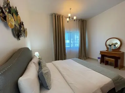 a bedroom with a bed and a mirror and a window at Home Away From Home - Barsha Heights in Dubai