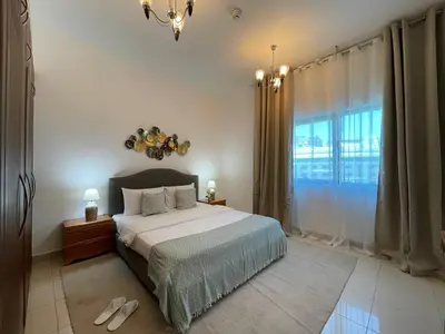a bedroom with a bed and a large window at Home Away From Home - Barsha Heights in Dubai