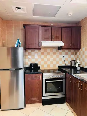 a kitchen with wooden cabinets and a stainless steel refrigerator at Home Away From Home - Barsha Heights in Dubai