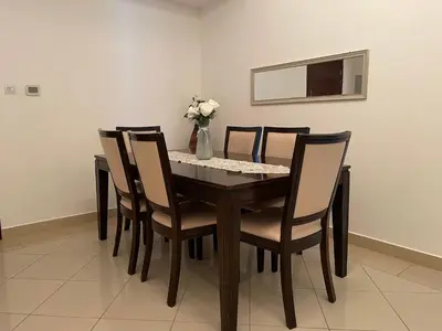 a dining room table with chairs and a vase of flowers at Home Away From Home - Barsha Heights in Dubai