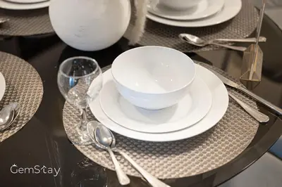 a table with a bowl and plates and spoons at Your Cosy Marina Retreat in Dubai