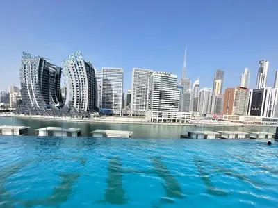 a large pool of water in front of a city at White and gold studio apartment in Binghatti Canal whit pool in Dubai