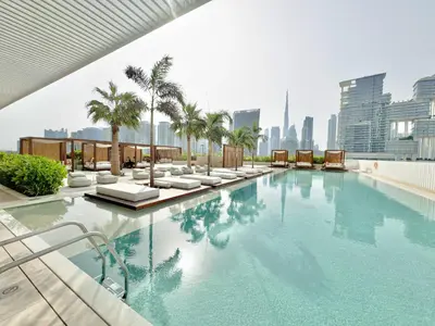 a swimming pool with chairs and palm trees on a building at Studio with Burj Khalifa View - Upside Living in Dubai