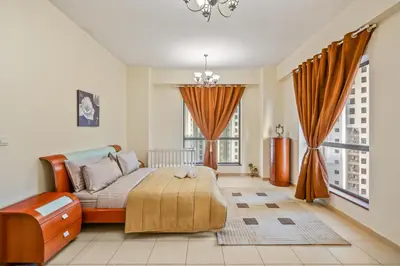 a bedroom with a bed and two windows at Cozy pad in the heart of Dubai on JBR beach! in Dubai