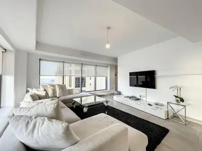a white living room with a couch and a tv at Rimal 3 - Incredible Two Bedroom in Dubai