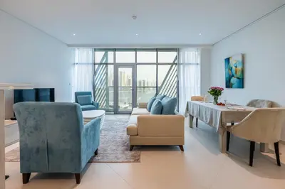 a living room with blue chairs and a table at Seven Palm, Private beach, Infinity Pool, High Floor 3BDR in Dubai