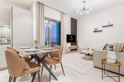 a dining room and living room with a table and chairs at STAY BY LATINEM Luxury 1BR Holiday Home CVR A1504 near Burj Khalifa in Dubai