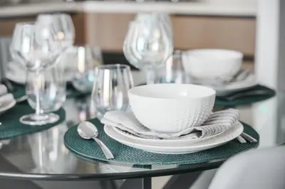 a table with a bowl and plates and wine glasses at Stayis -1 BR Burj Khalifa View Partial in Dubai