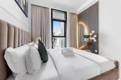 a bedroom with a large white bed with a window at Stayis -1 BR Burj Khalifa View Partial in Dubai