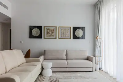 a living room with a white couch and three pictures on the wall at La Vie, JBR private beach, private parking and pool in Dubai