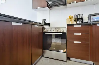 a kitchen with wooden cabinets and a stainless steel oven at Modern Studio Sports City Pool & City Views in Dubai