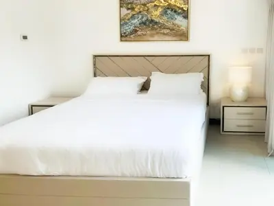 a bedroom with a white bed and a painting on the wall at Full lake View 1bk Apartment in JLT 4 ppl early & late check in 10mn to Marina metro station in Dubai