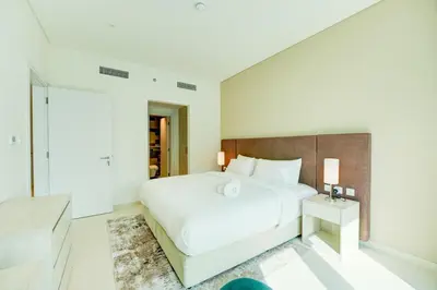 a white bedroom with a large bed and a mirror at Seven Palm 1 Bed with Rooftop Infinity Pool in Dubai