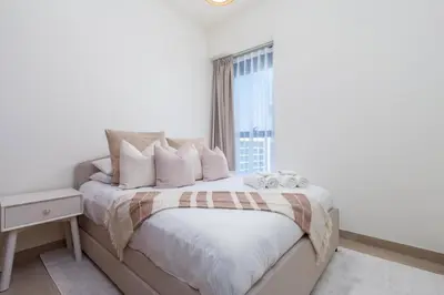 a white bedroom with a large bed with a window at 2bdr 12min from Downtown in Dubai