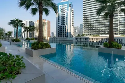 a large swimming pool with palm trees and buildings at Luxury Glam Studio Near Burj Khalifa Downtown in Dubai