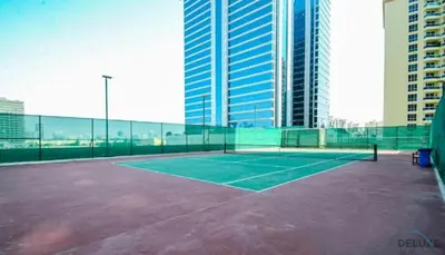 a tennis court in front of some tall buildings at Comfortable Studio at Lago Vista A Dubai Production City by Deluxe Holiday Homes in Dubai