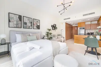a white bedroom with a white bed and a kitchen at Comfortable Studio at Lago Vista A Dubai Production City by Deluxe Holiday Homes in Dubai