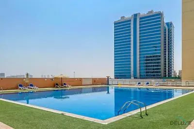 a large pool with chairs and a tall building at Comfortable Studio at Lago Vista A Dubai Production City by Deluxe Holiday Homes in Dubai