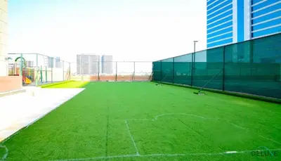 a tennis court with green grass on a building at Comfortable Studio at Lago Vista A Dubai Production City by Deluxe Holiday Homes in Dubai