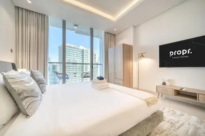 a bedroom with a large white bed and a flat screen tv at Canal-View Serenity: Modern Studio in Sterling in Dubai