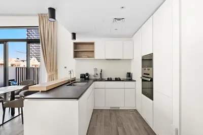 a kitchen with white cabinets and a table with chairs at ALiving Stylish 1BR Apartment I Fully Furnished with Balcony I Belgravia Square, JVC in Dubai