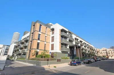 an apartment building on a street with parked cars at ALiving Stylish 1BR Apartment I Fully Furnished with Balcony I Belgravia Square, JVC in Dubai