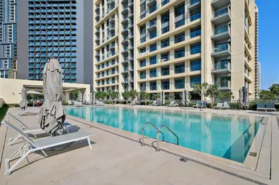 a pool with a chair and an umbrella next to a building at Silkhaus Luxurious 1 BDR Stunning View in Dubai