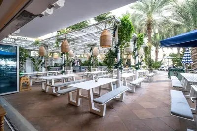 a restaurant with white tables and benches and plants at Seaview-Shoreline4-Palm Jumeirah in Dubai