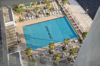 an overhead view of a swimming pool with chairs and palm trees at ALiving Deluxe Studio I DAMAC Maison Prive, Business Bay -1204 in Dubai