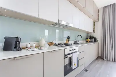 a white kitchen with white cabinets and appliances at Frank Porter - Noor 3 Midtown in Dubai