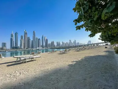 a group of benches on a beach with a city at Seaside Splendor: Luxe Retreat at Emaar Beachfront in Dubai