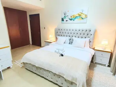 a bedroom with a large white bed and two night stands at JBR Retreat: Stylish Views in Dubai