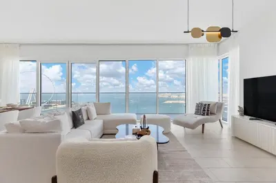 a living room with white furniture and large windows at Maison Privee - Upscale Apt w/ Open Sea and Bluewaters Vws in JBR in Dubai
