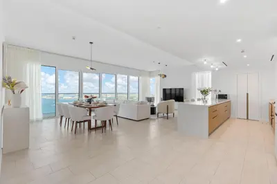 a white living room with a table and a kitchen at Maison Privee - Upscale Apt w/ Open Sea and Bluewaters Vws in JBR in Dubai